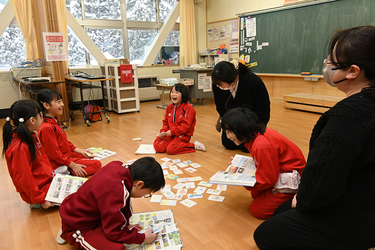 資料集を見ながらかるた取りをする阿仁学園の１・２年生