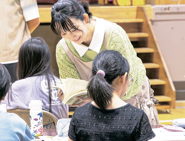 作文を書く児童に声をかける久米絵美里さん