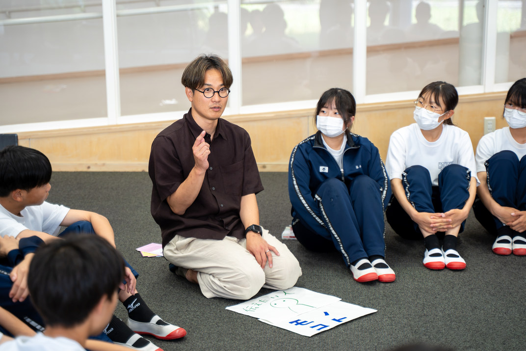 輪になって座る生徒たちに話しかける講師の山内佑輔さん