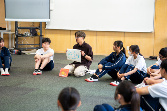 床に座って物語を読み込みながら教訓を出し合う生徒たち