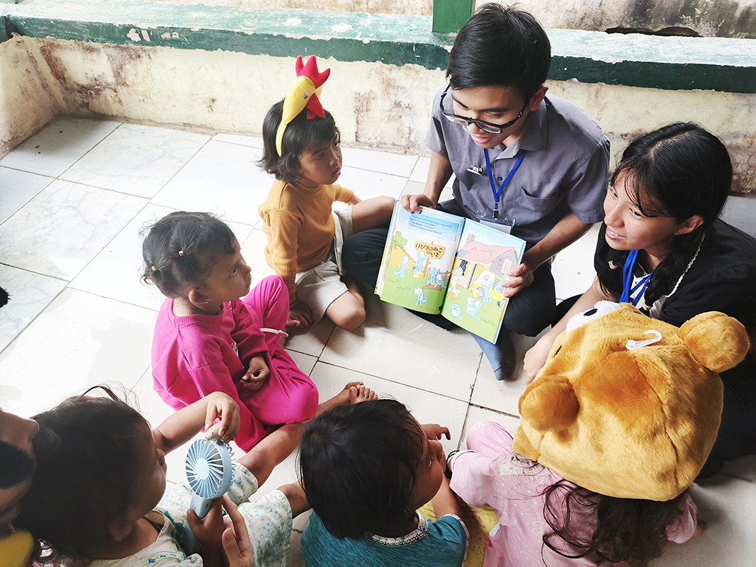 貧困の子どもたちに読み聞かせを行うインドネシア青年